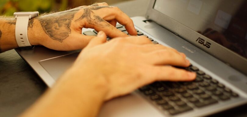 Hands typing on a laptop submitting a cosmetic notification online