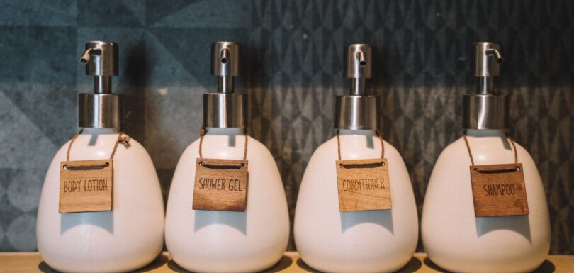 Four unbranded ceramic pump bottles labelled with wooden tags on a shelf