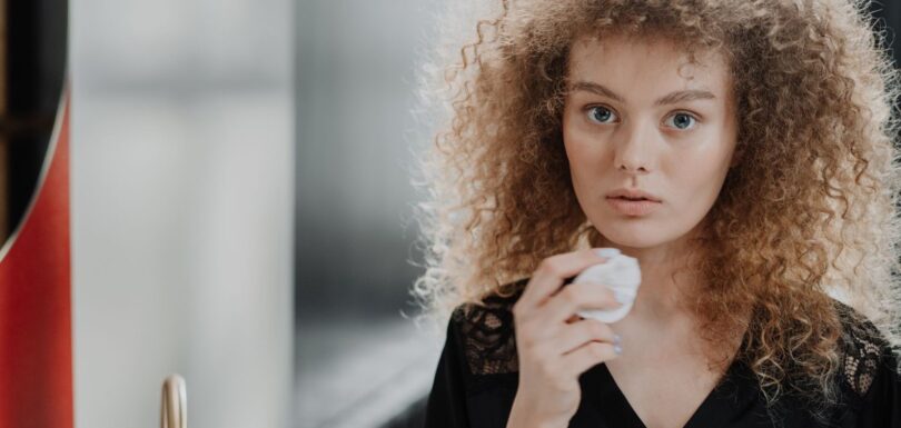 Person applying toner to the face with a cotton pad