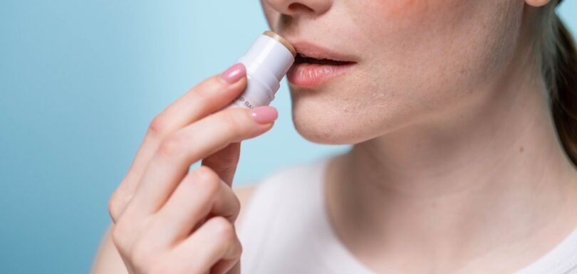 Lip balm sticks and a tinted lip oil on a plain background