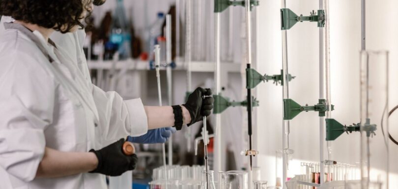 Two scientists working with laboratory glassware and pipettes
