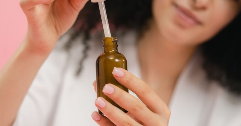 Person holding an amber serum bottle and a dropper