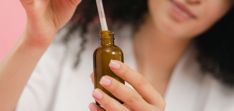 Person holding an amber serum bottle and a dropper