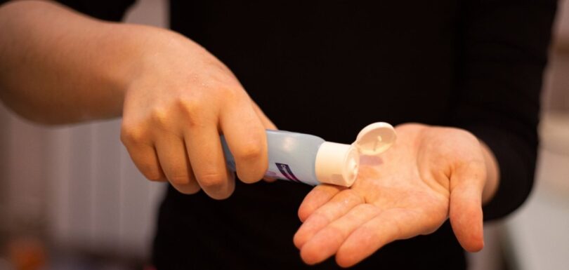 Person dispensing gel from a tube onto their palm