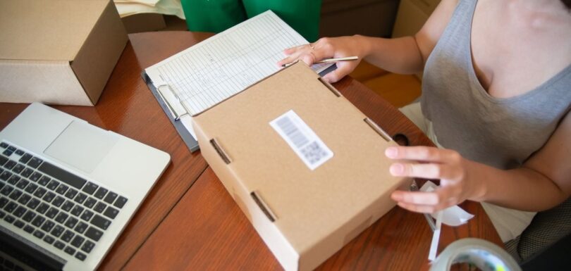 Person packing an online order beside a laptop
