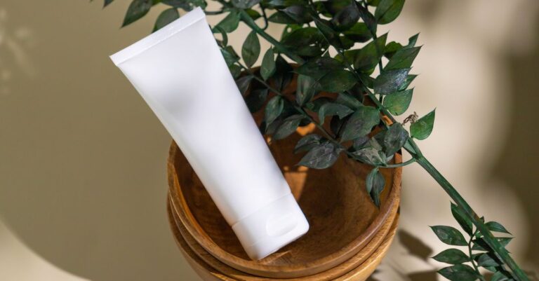 White cosmetic tube beside a green plant